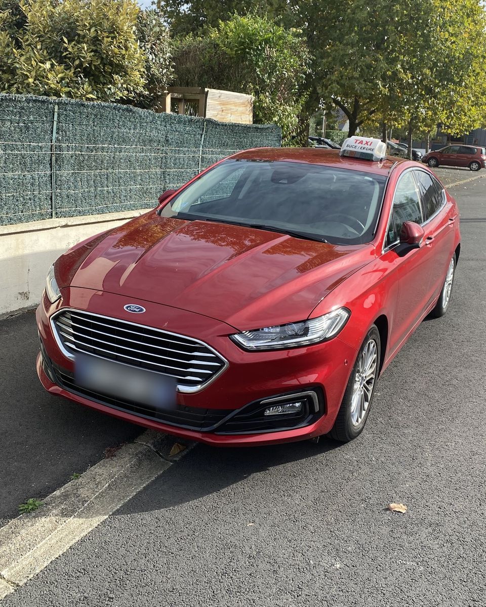 La Ford Mondeo rouge de Taxi Morgane, lumineux « Taxi Sucé / Erdre » sur le toit, garée dans une rue arborée.